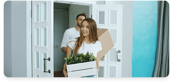 Couple carrying moving boxes through a doorway